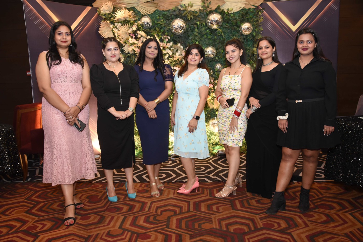 Colleagues at an office party in front of a floral backdrop
