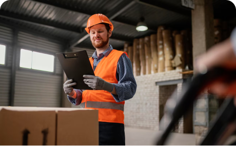 Warehouse worker in a safety vest reviewing a clipboard