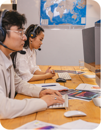 Two agents wearing headsets working at a shared desk
